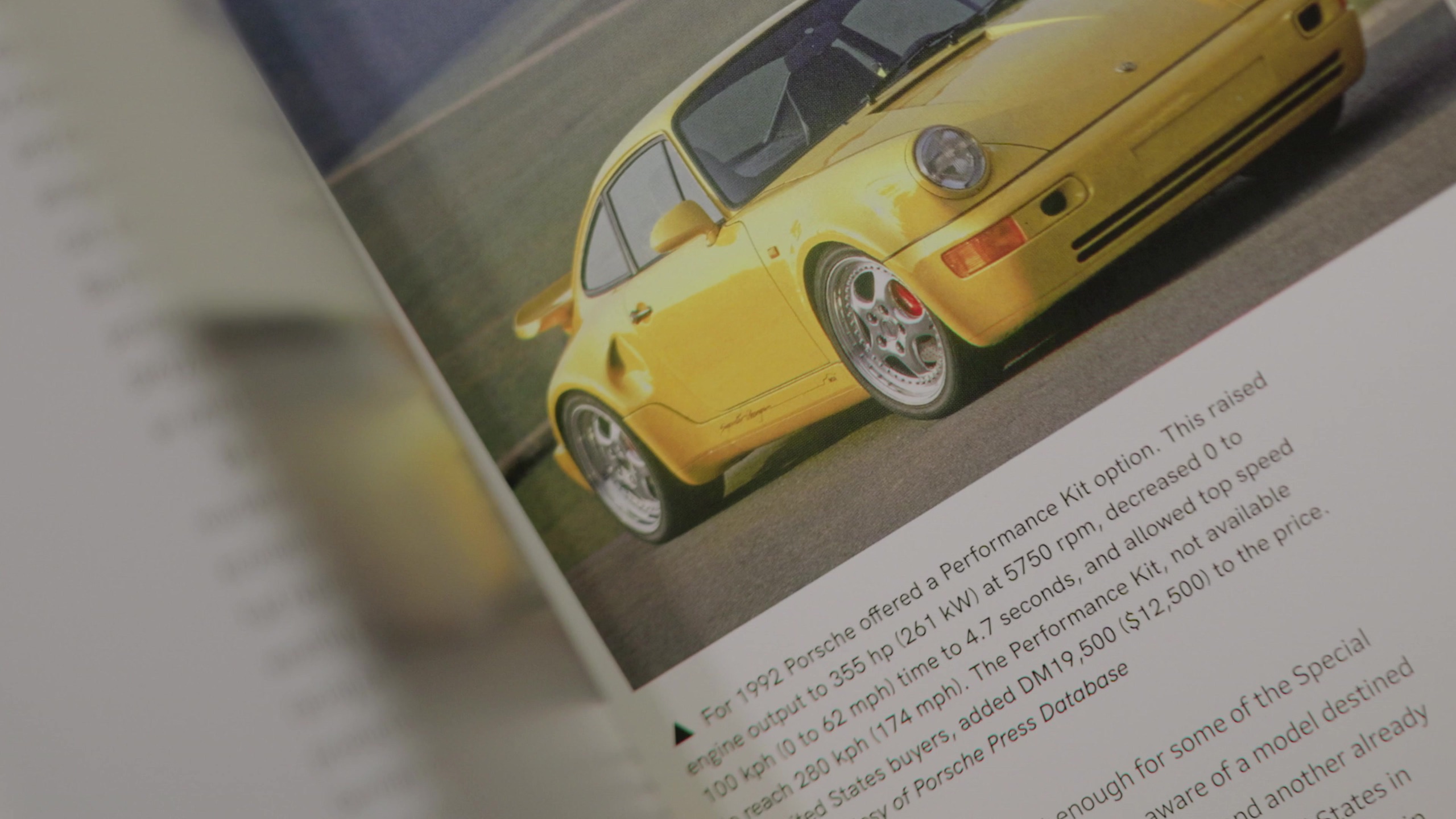 Open Porsche book with a yellow 911 on the page