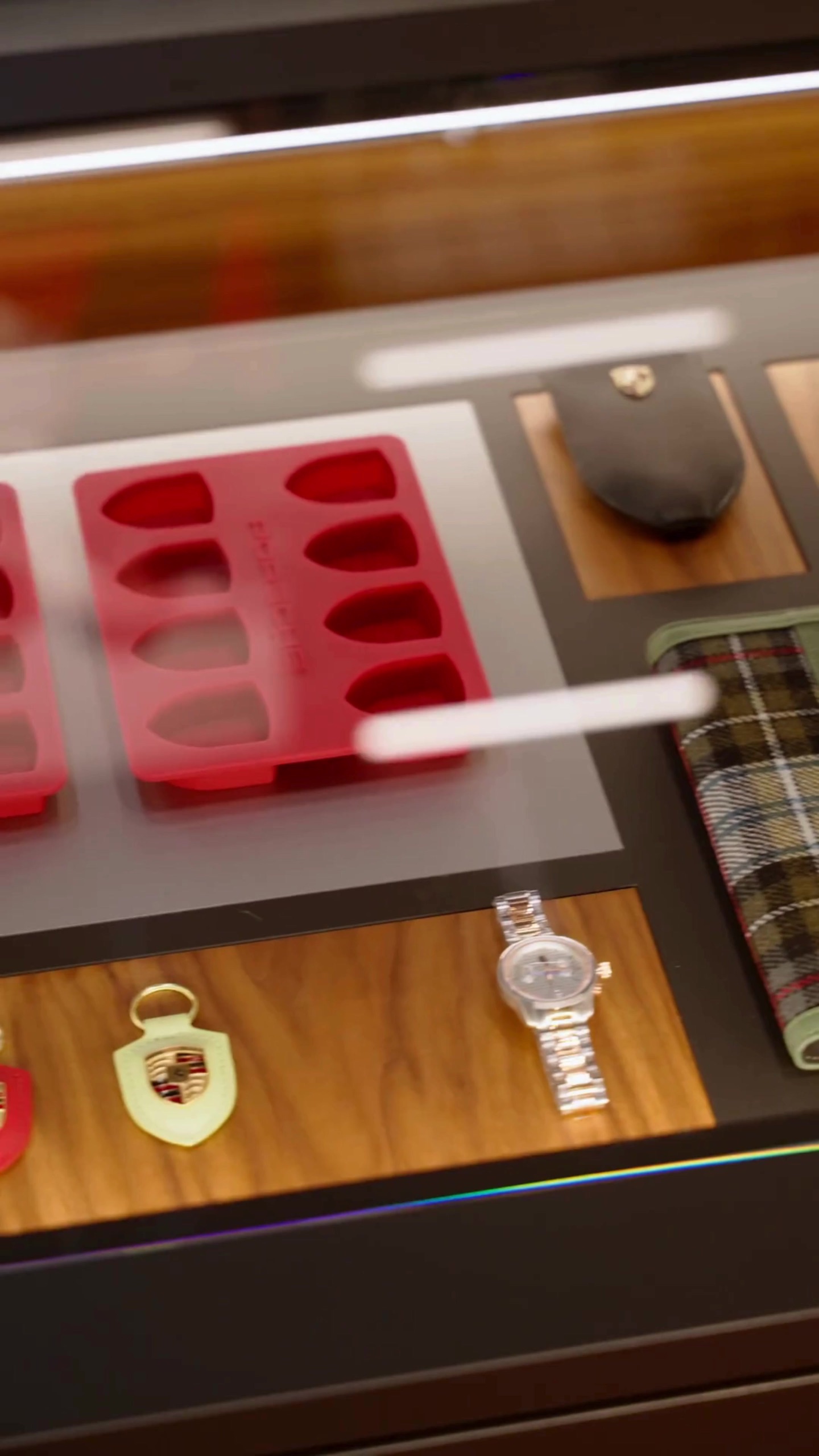 Porsche accessories and a watch arranged on a display tray