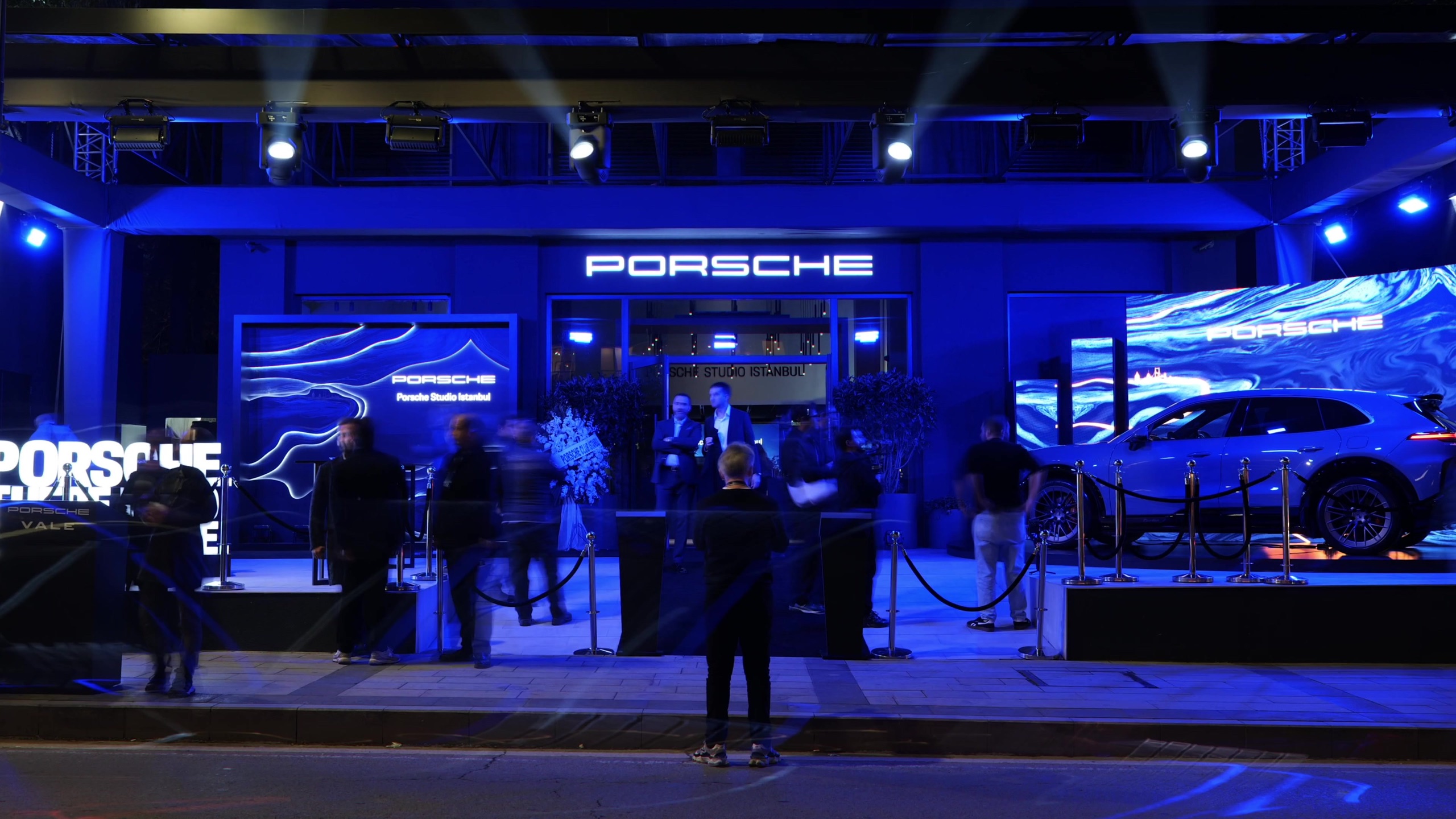 Studio façade lit in blue with the Porsche sign at night