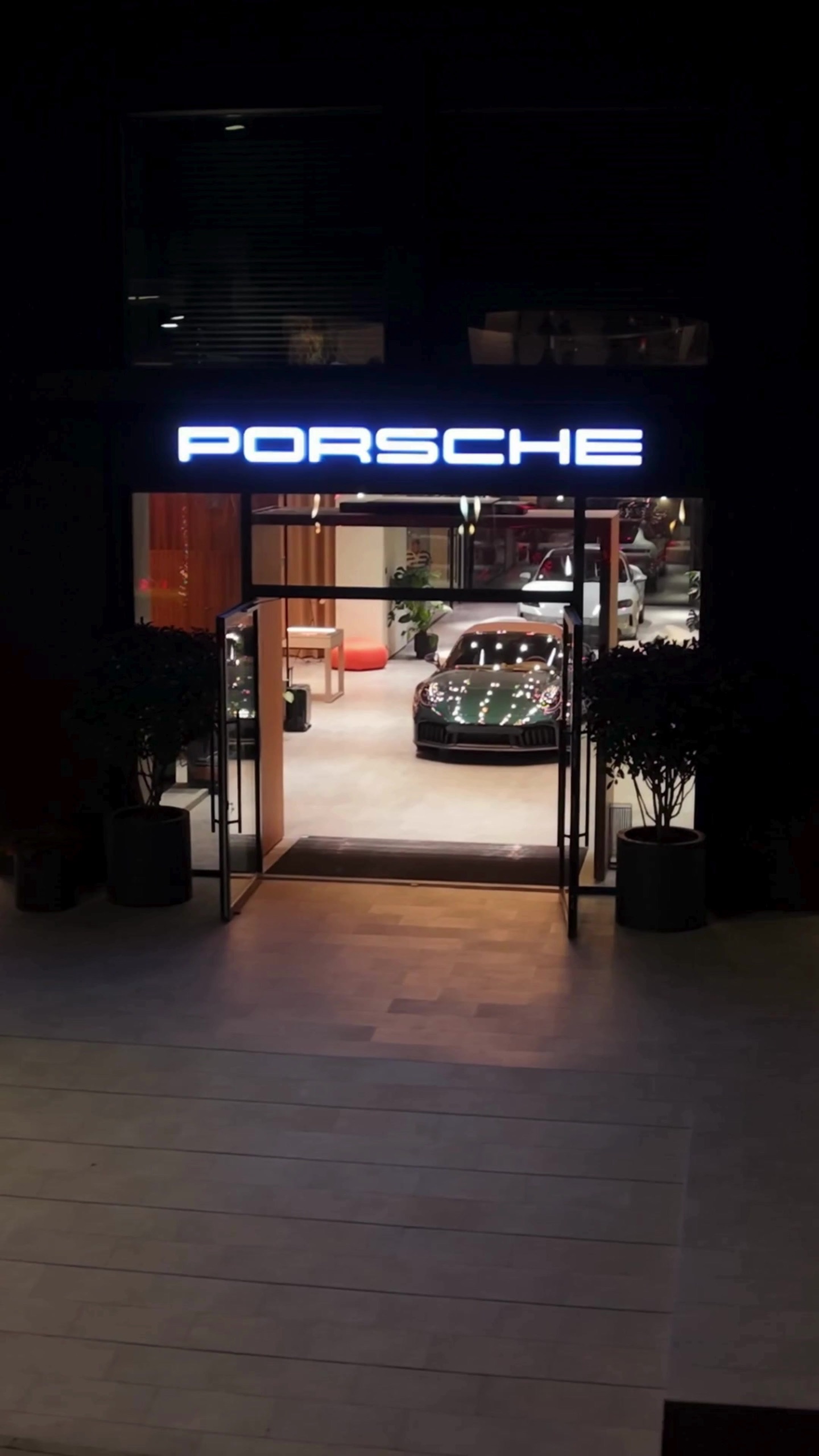 Illuminated Porsche signage above the studio entrance at night