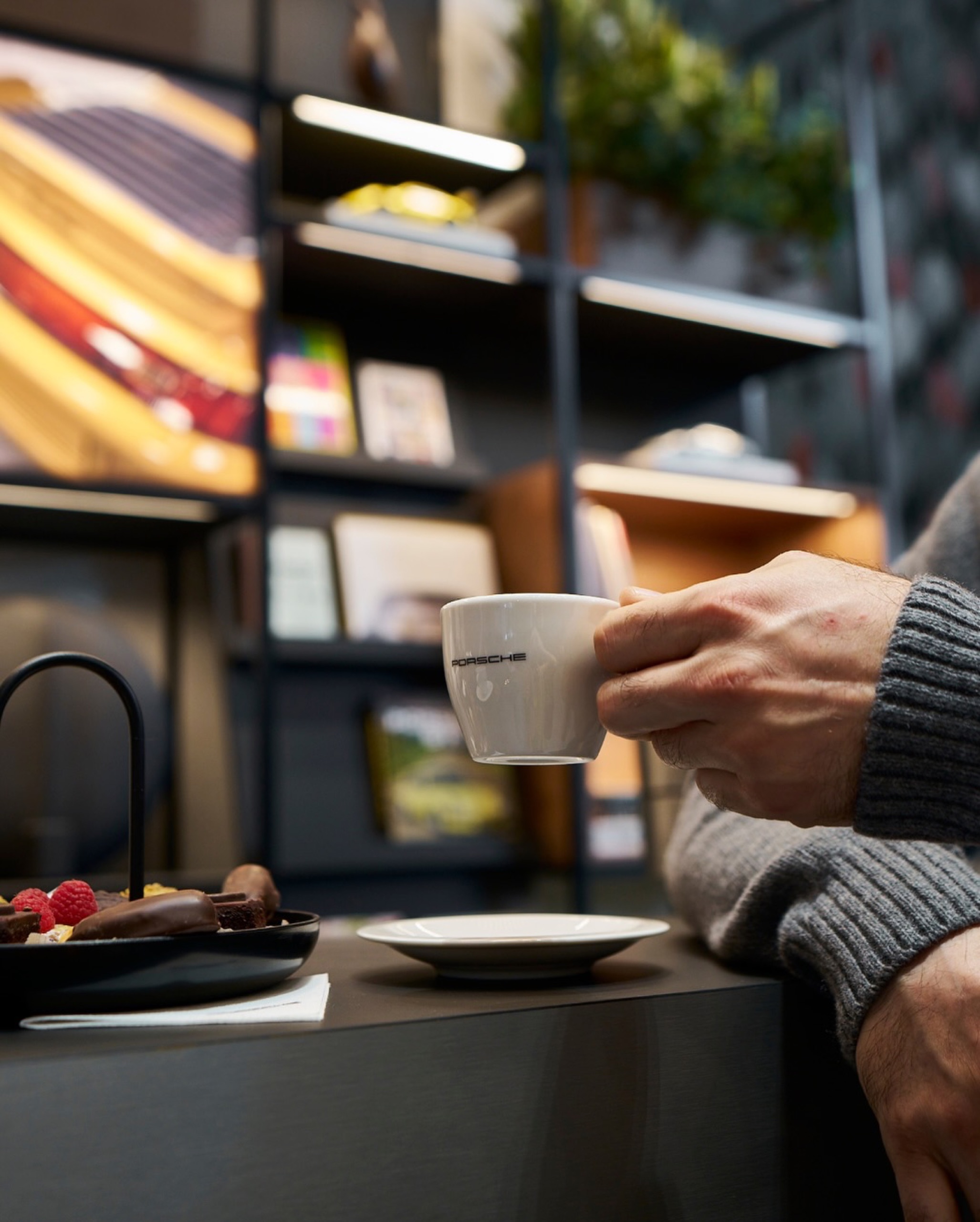 Hand holding a coffee cup at the Porsche Café counter