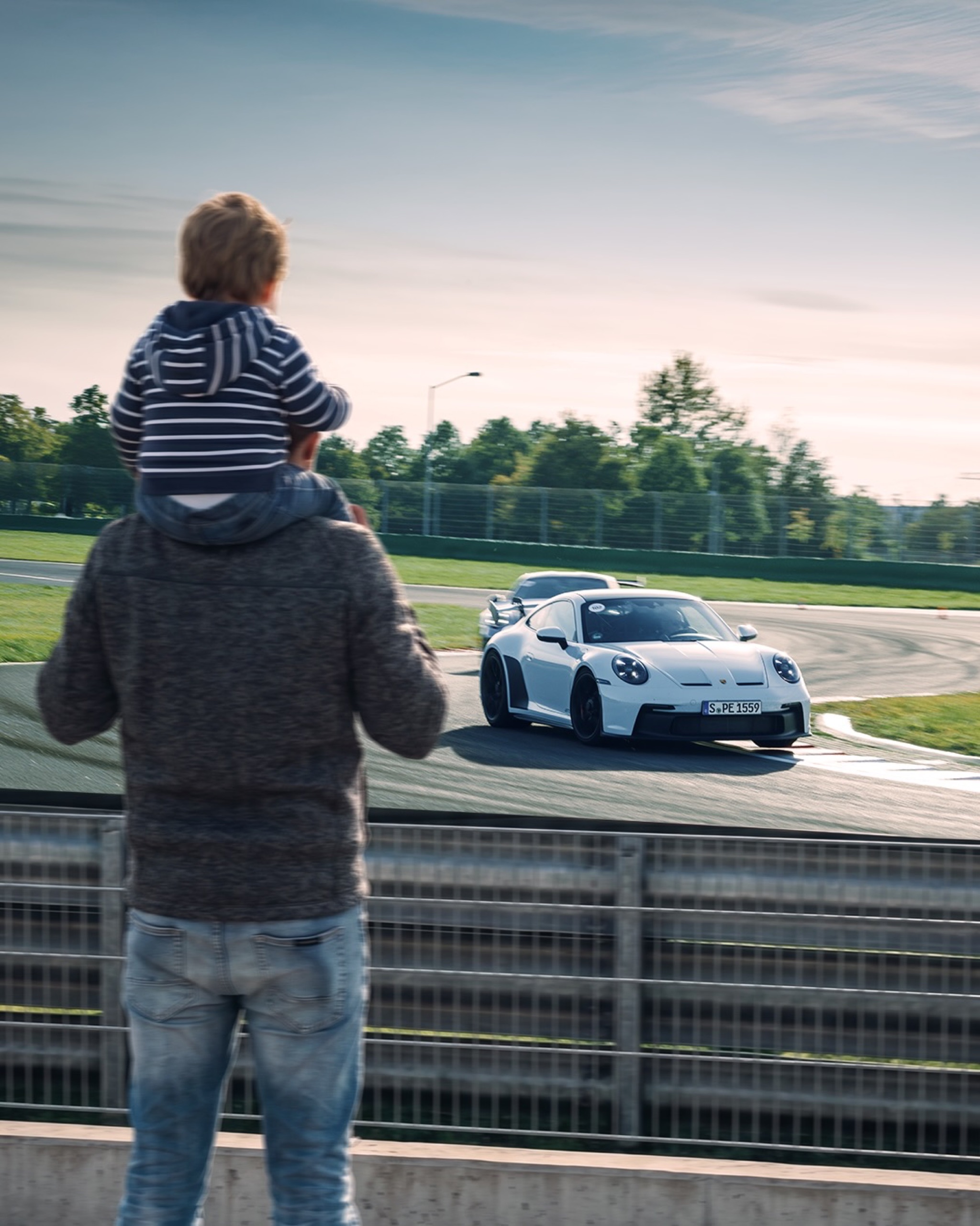 Father and child watching a 911 on the track