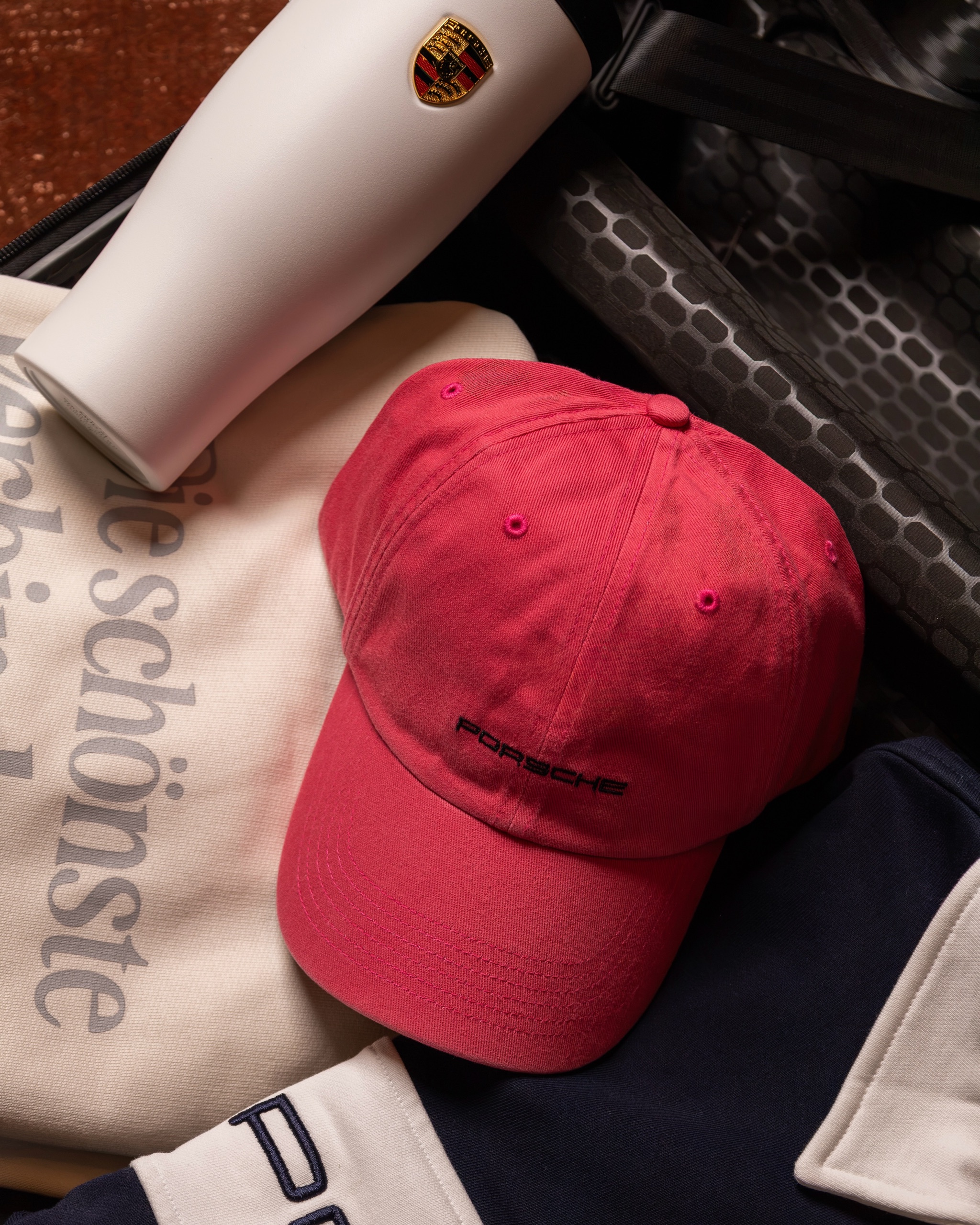 Lifestyle collection styled as a flat lay with cap, polo and bottle, 2